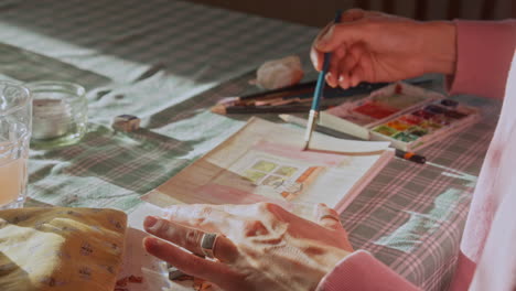 Painter-washing-water-colour-onto-page,-artist-at-work,-close-up-shot,-creativity