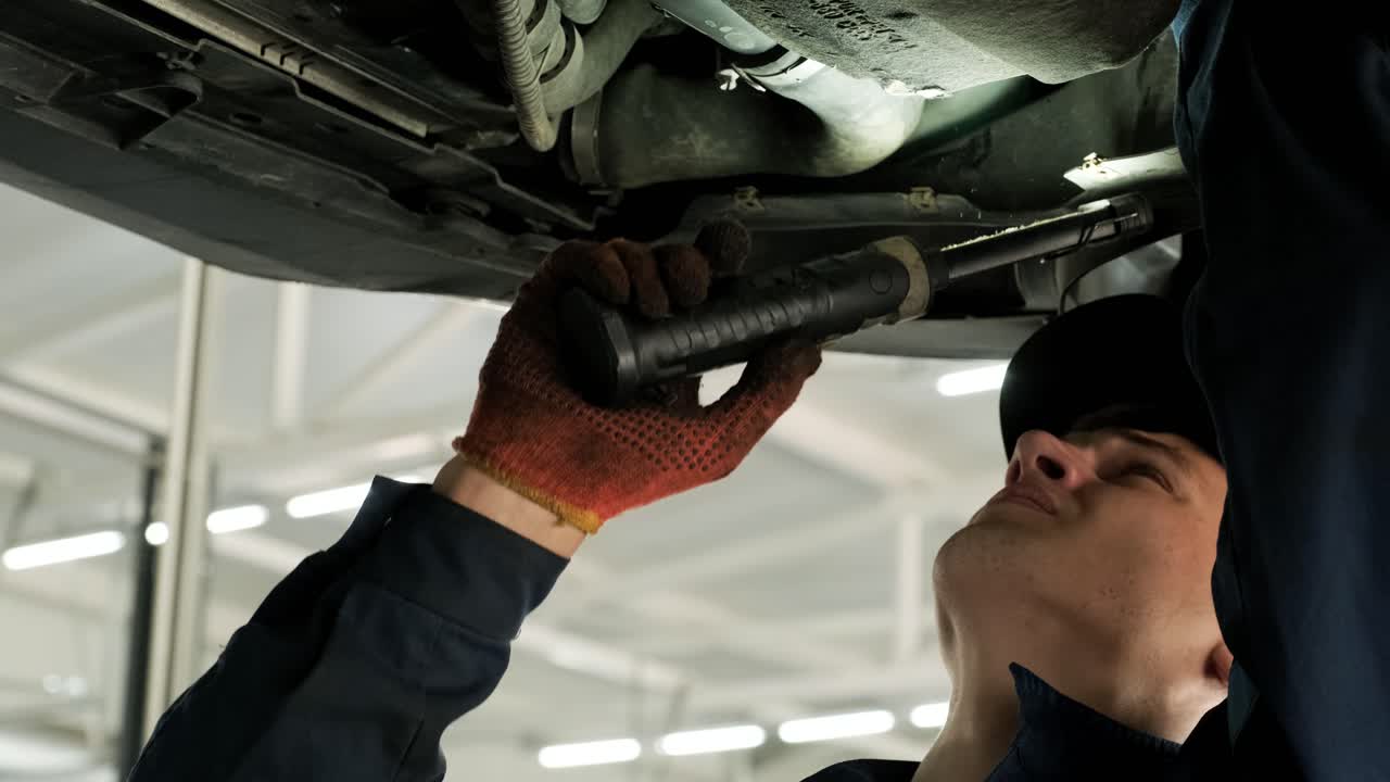 inspección del tren de aterrizaje del automóvil por parte de un mecánico