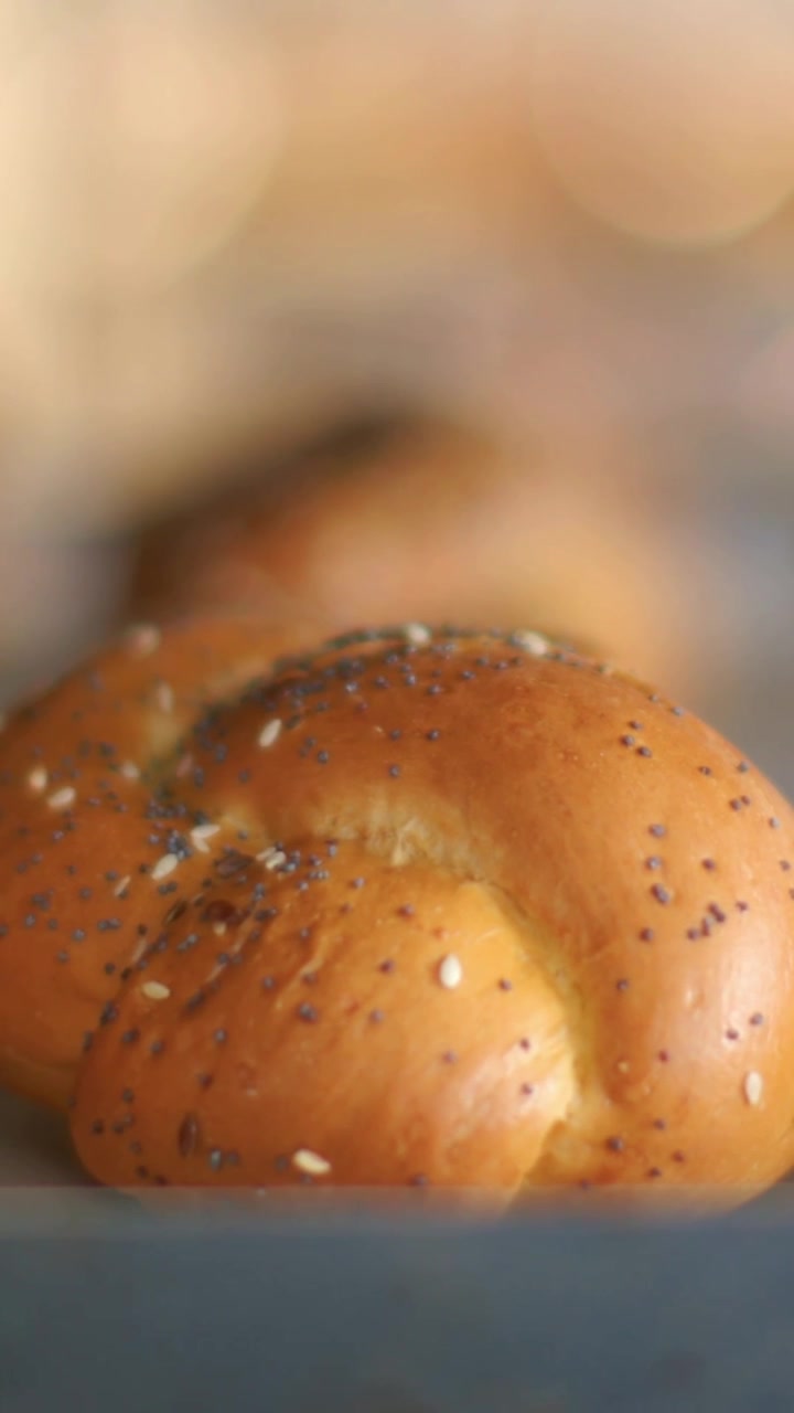 Vertical video: Camera pulling focus framing braided seed roll at bakery showing poppy sesame seeds