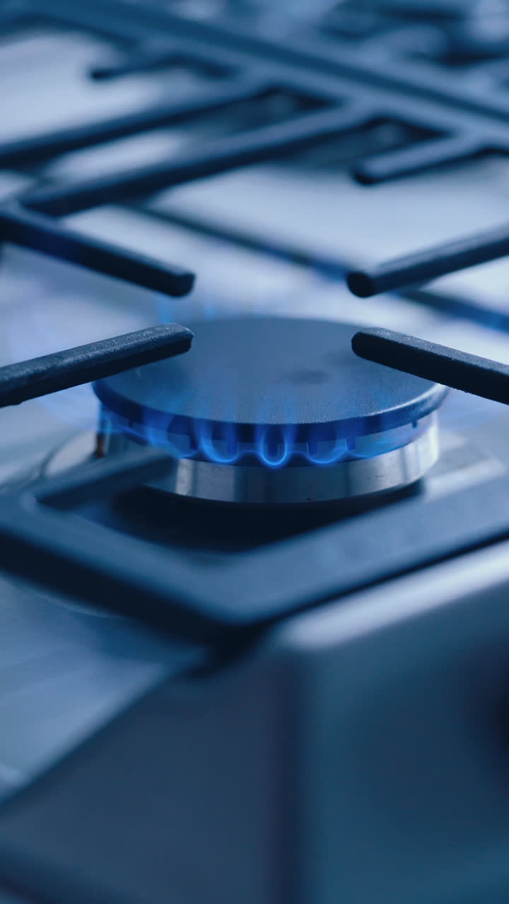 Gas Stove In The Kitchen. Burning blue flames of gas on cook top under grills in kitchen