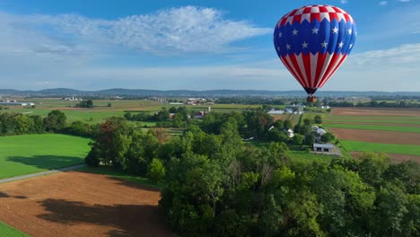 Luftaufnahme-Eines-Amerikanischen-Heißluftballons,-Der-Im-Sommer-über-Eine-Malerische-Landschaft-Mit-Waldbäumen-Und-Feldern-Fliegt---Amerikanische-Landschaft