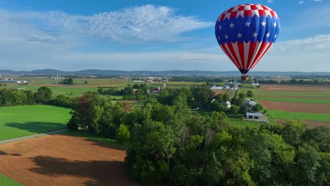 tomada en órbita aérea de un globo de aire caliente estadounidense volando sobre un paisaje pintoresco con árboles de bosque y campos en verano - campo estadounidense