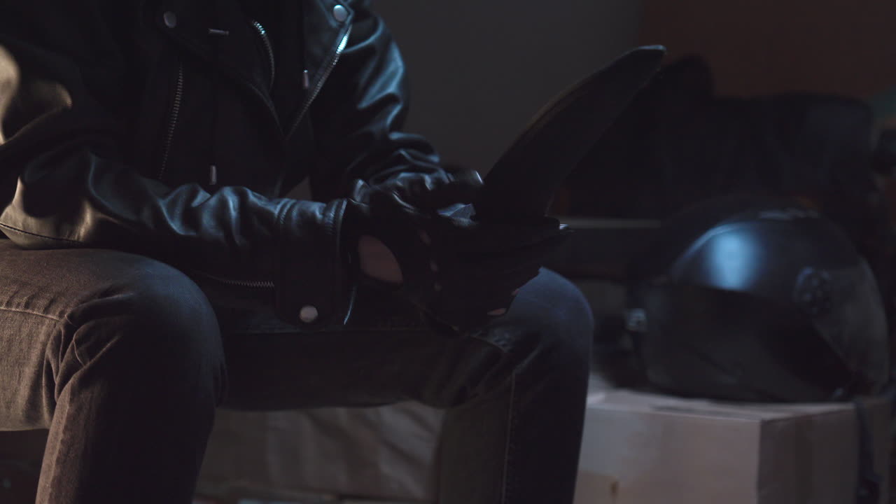 una persona con guantes de cuero negro saca un enorme cuchillo de una bolsa de lona