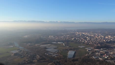 Blick-Auf-Die-Berge-Von-Annemasse-Und-Umgebung-Vom-Salève-Aus-An-Einem-Sonnigen-Tag-Mit-Leichtem-Nebel-Und-Strahlender-Sonne,-Schwenk-Nach-Rechts,-Weitwinkelaufnahme