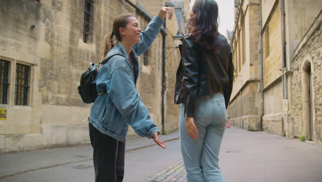 same sex female couple pose for photo making shape of frame with hands as they visit city together