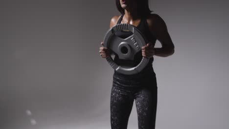 fotografía de estudio de una mujer madura con ropa de gimnasia levantando pesas para ejercicios de cardio 2
