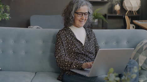senior woman using laptop on sofa