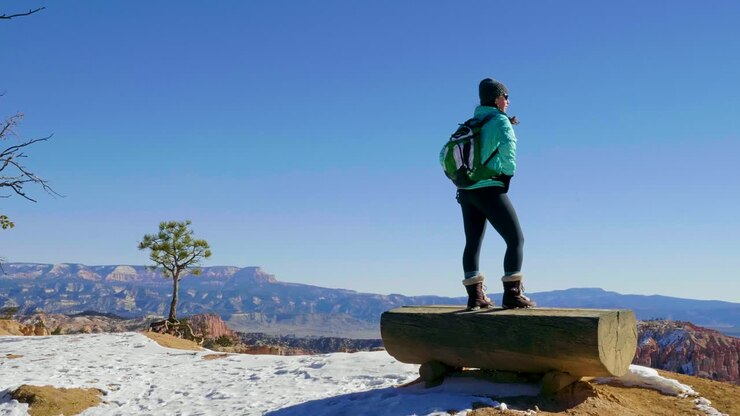 Girl woman standing on presipus looking out at the red rocks formation and snow near Bryce Canyon in southern Utah