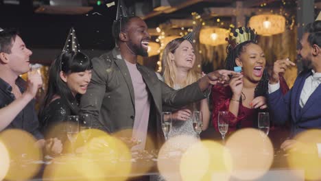 wide shot of friends celebrating new year's eve with confetti and party blowers