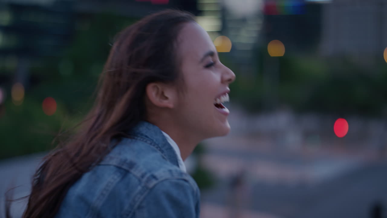 retrato de cerca mujer hispana joven y animada riendo feliz mujer independiente disfrutando de un estilo de vida urbano exitoso en la ciudad noche cámara lenta viento soplando el cabello
