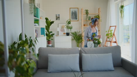 mujer feliz regando flores en casa
