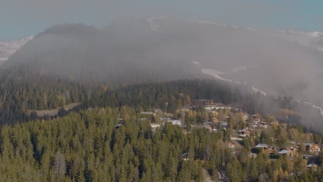 cinematic aerial over beautiful swiss resort with green lush pine forests in swiss mountains, switzerland