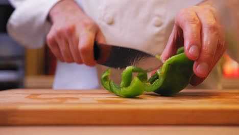 the cook cuts the green pepper on a wooden board