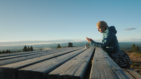 A-Woman-Sits-At-A-Table-Uses-Her-Teléfono-High-In-The-Mountains-Of-Norway-4k-Video