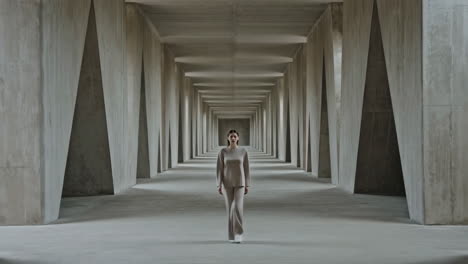 woman walking in a long concrete hallway