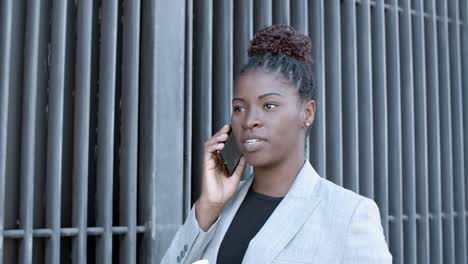 static shot of a confident african american businesswoman talking on mobile phone outside in the street