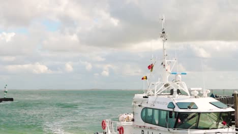 rotes und weißes lotsenboot segelt vom offenen blauen meer mit wolken und blauem himmel in den hafen von seeland in den niederlanden