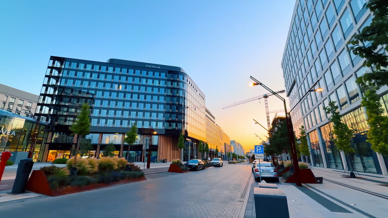 Bratislava, Slovakia - June 5, 2025: Sunset over urban street. Bright street lined with trees and modern buildings, capturing the vibrant atmosphere of the area at sunset
