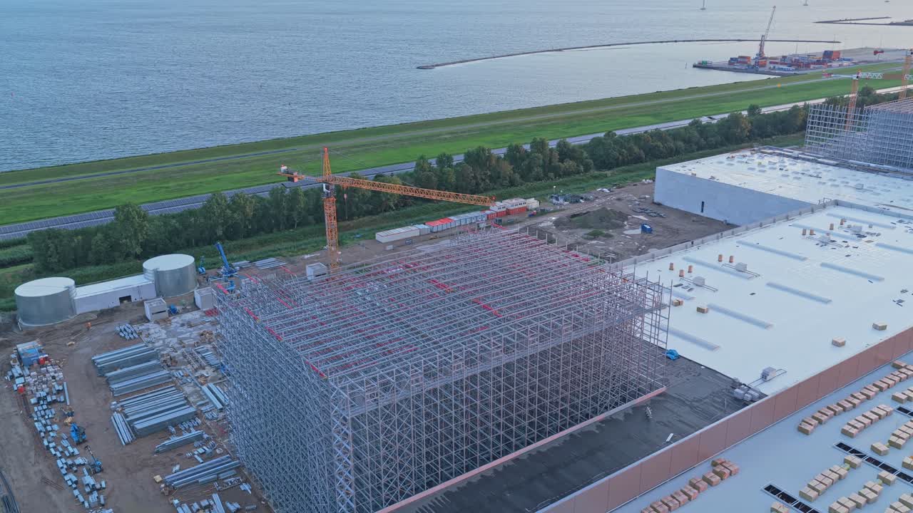 Scena industriale all'alba, gru e impalcature delineano un nuovo centro di distribuzione