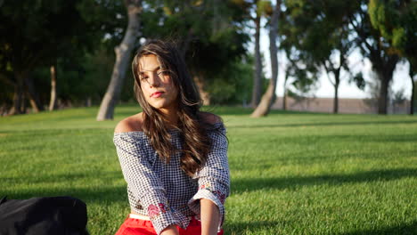 Beautiful-young-hispanic-college-student-resting-on-a-grassy-park-field-between-classes-on-campus