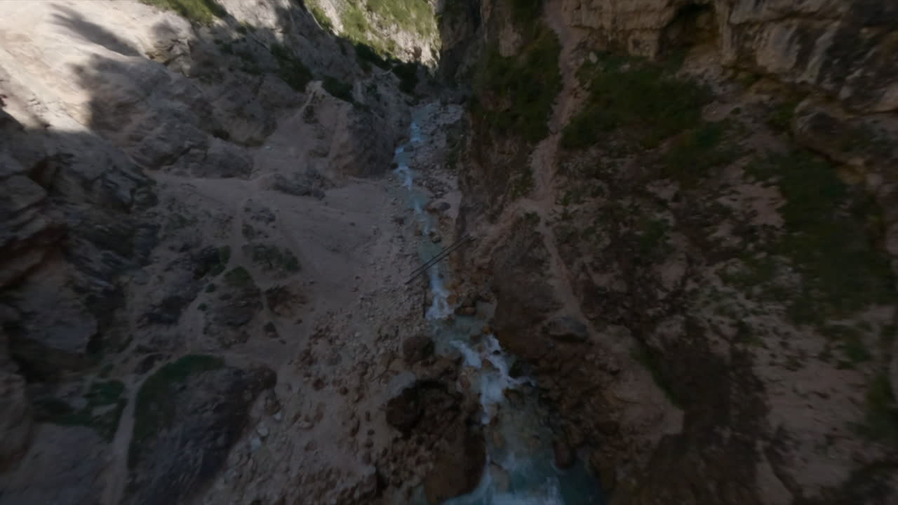 Crazy drone racing freestyle flight over creek flowing in narrow gorges, Italian mountains