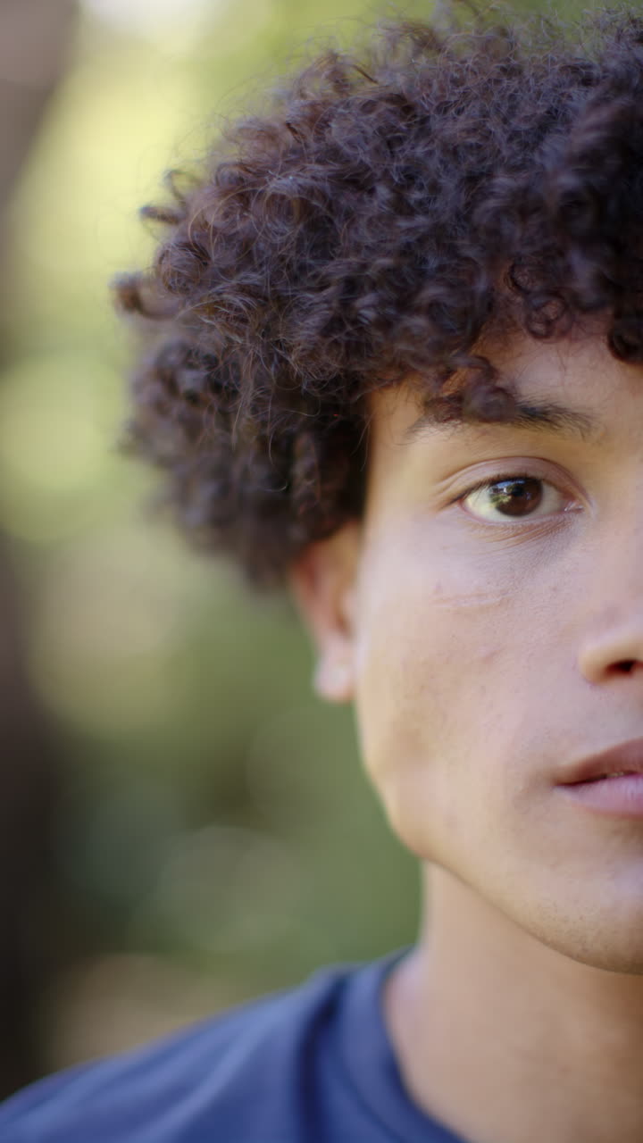 Vertical video: Young man outdoors, gazing thoughtfully, enjoying nature and fresh air
