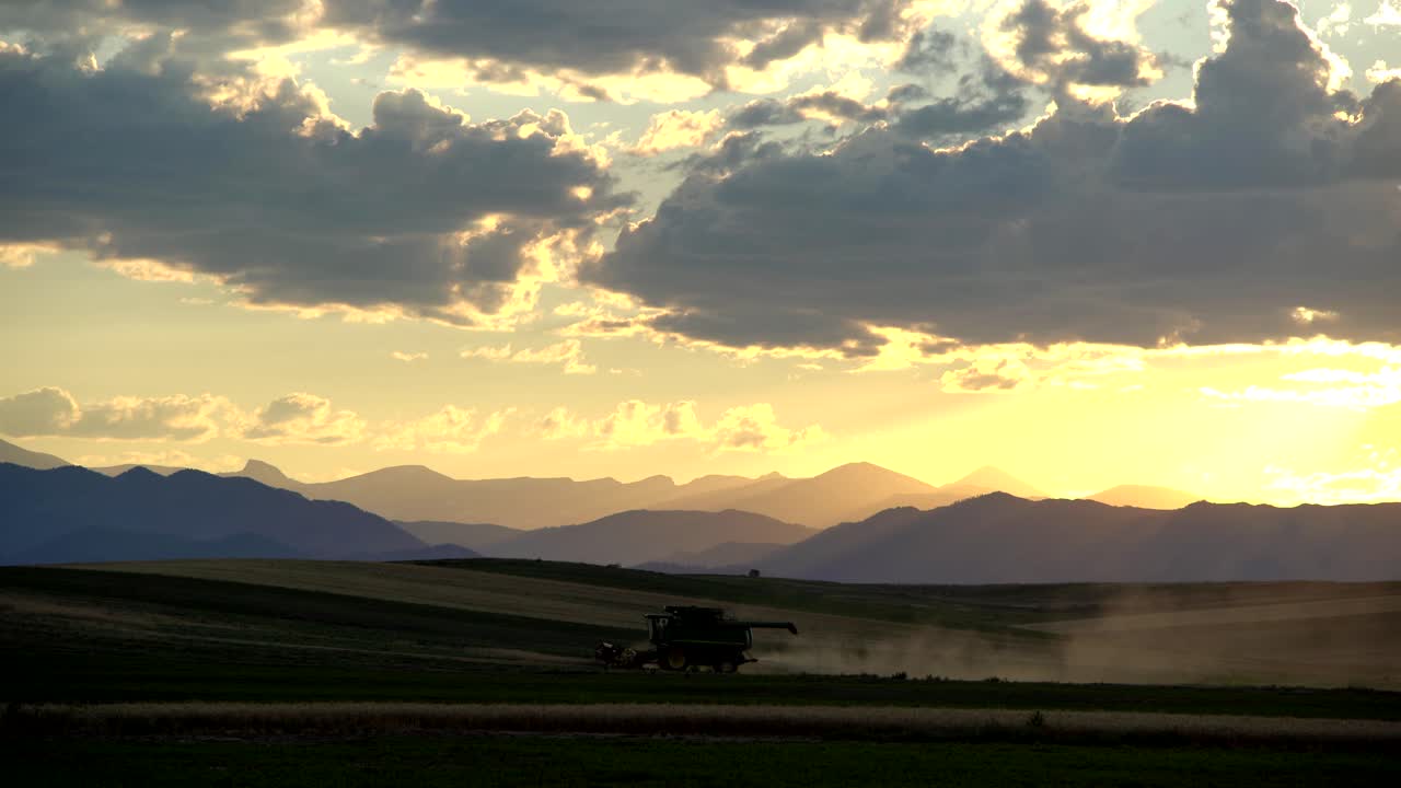 산과 일몰을 배경으로 시골 콜로라도의 결합 수확기