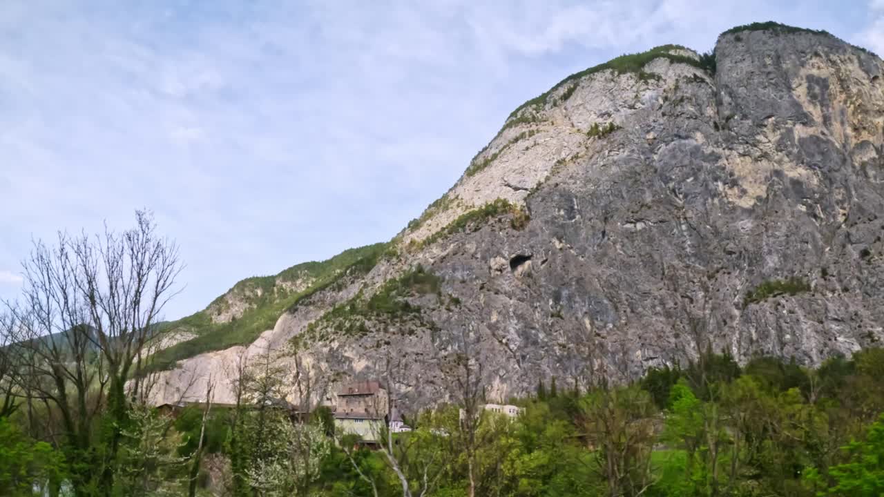 Limestone cliff rises above spring trees in the Karwendel mountains along the Innsbruck–Munich route, showing classic glacial rock faces, karst features, near the protected Alpenpark border region