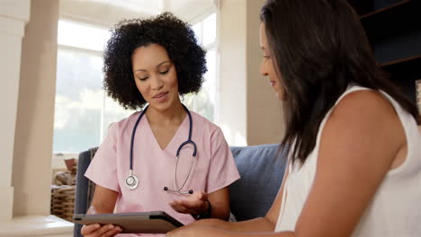 nurse in pink scrubs discussing medical information with patient using tablet