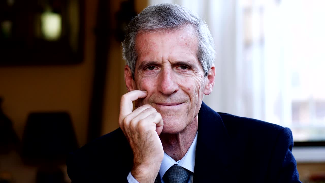 el viejo gerente confiado en su oficina mirando a la cámara