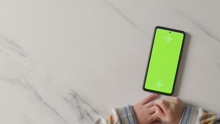 Ripresa in studio dall'alto di un bambino che usa uno smartphone con schermo verde 6