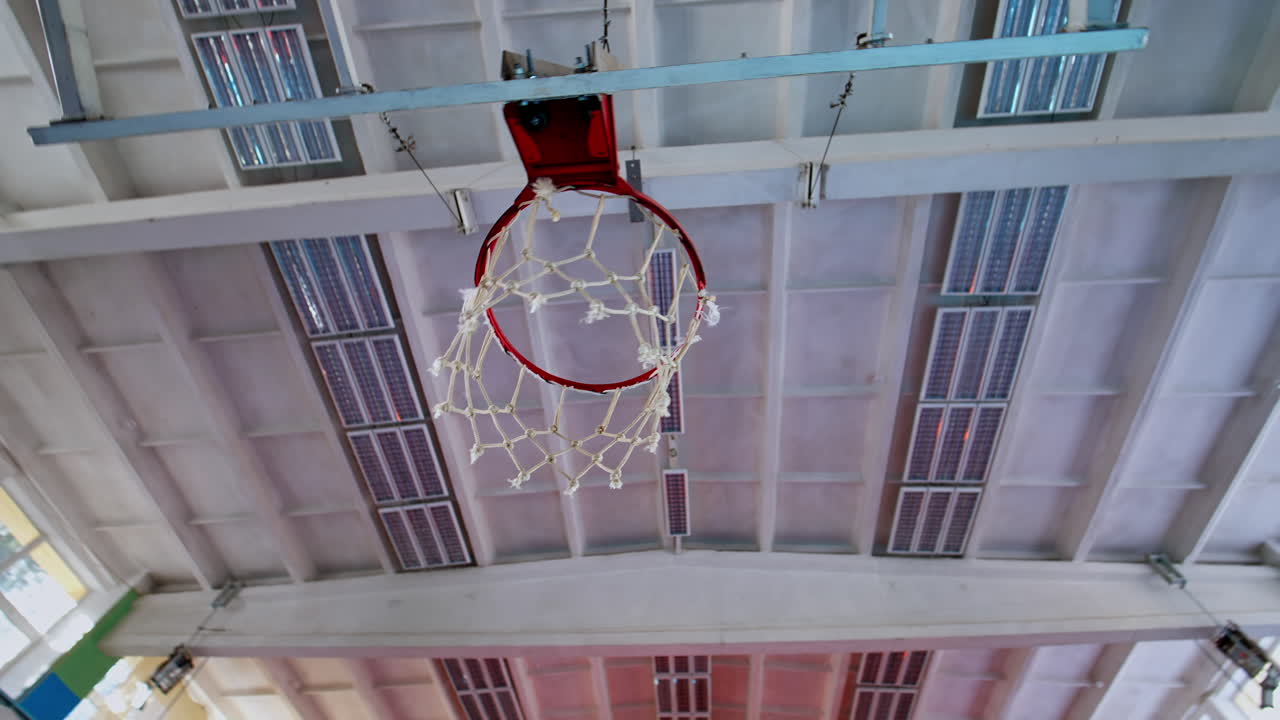 Basketball hoop on empty court. Upward view of basketball hoop indoors
