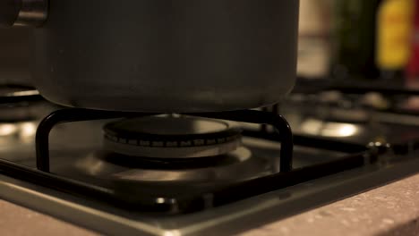 turning gas stove off with pot on top close up, slow motion