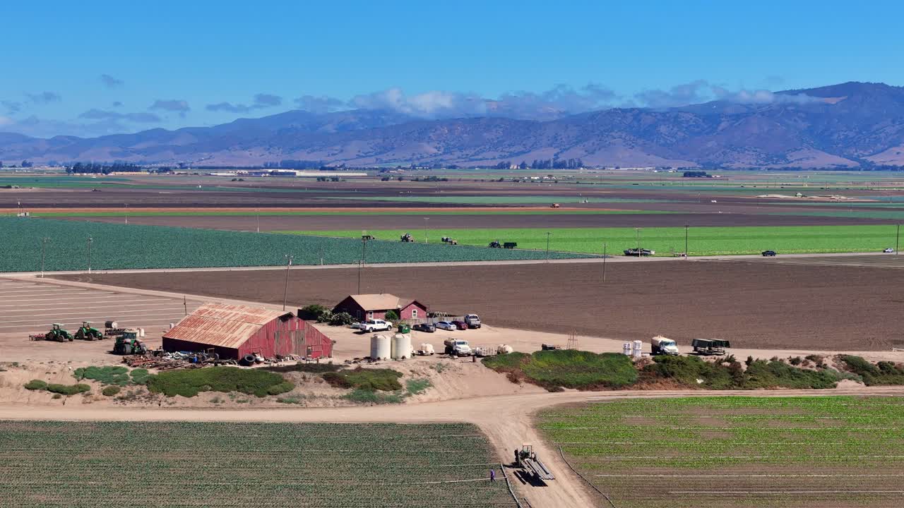 Large barn surrounded by fields and trucks in Salinas Valley agriculture zone, USA