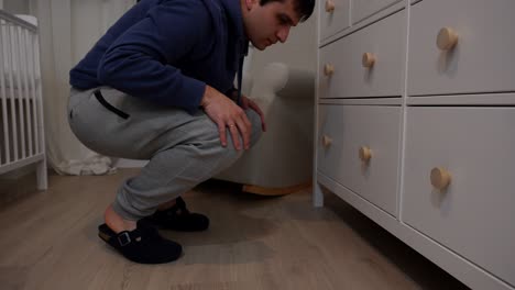 man closing drawers of a dresser in the room of a baby