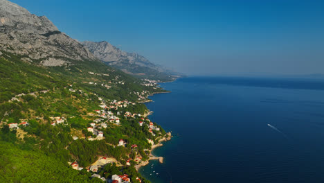 Toma-Aérea-De-Seguimiento-De-Un-Barco-Conduciendo-Por-La-Costa-De-La-Riviera-De-Makarska-En-Croacia.