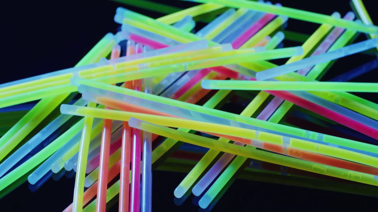 animación de múltiples palos de brillo de neón coloridos sobre un fondo negro