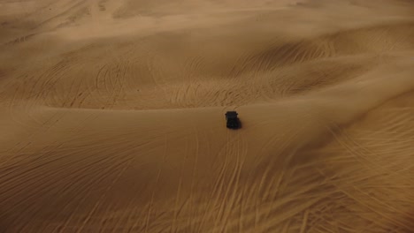 AERIAL---Off-road-4x4-truck-in-Ica-desert-sand-dunes,-Peru,-forward-tilt-down