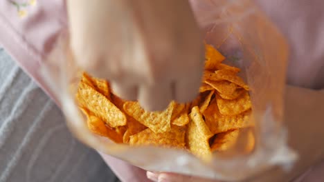 woman reaching into a bag of spicy tortilla chips