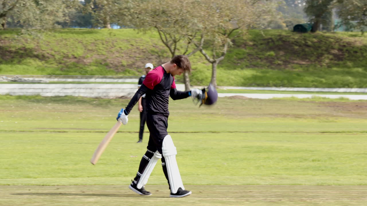 Two teams of multiracial male cricket players playing cricket, batter hitting ball with bat on pitch