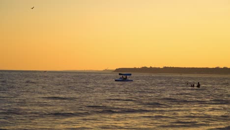 catamaran and people in the evening sea. blue boat floating on the background of the calm sea at sunset. people swimming in water.
