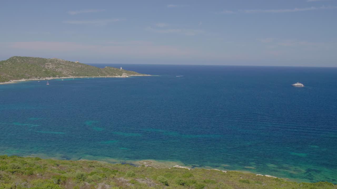 Saint-Florent Corsica coast sunny beat yacht view of crystal clear turquoise water, rocky shorelines under a bright blue sky serene Mediterranean landscape northern Corsican seaside