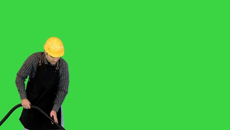 construction worker working on the site with a vacuum cleaner and smiling on camera on a green screen, chroma key