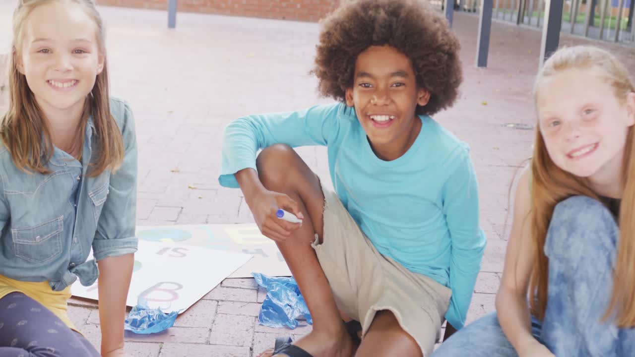retrato de video de escolares diversos y felices haciendo carteles de protesta en el patio de la escuela, espacio de copia.