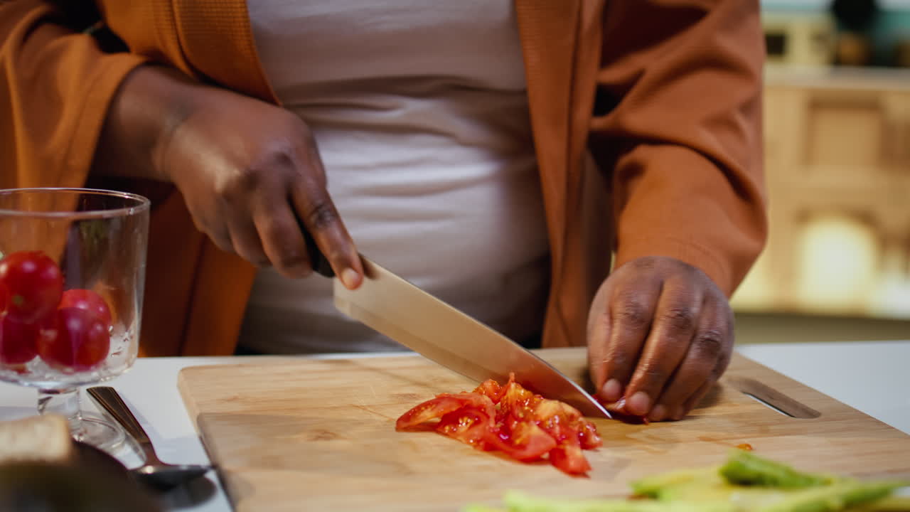 Close up of food vlogger chopping cherry tomatoes on cutting board