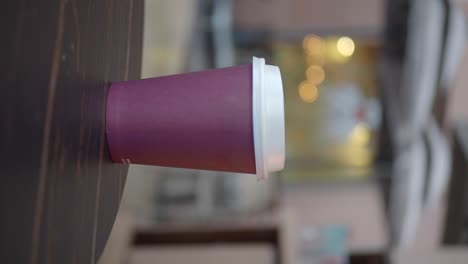 a purple paper coffee cup sitting on a wooden table