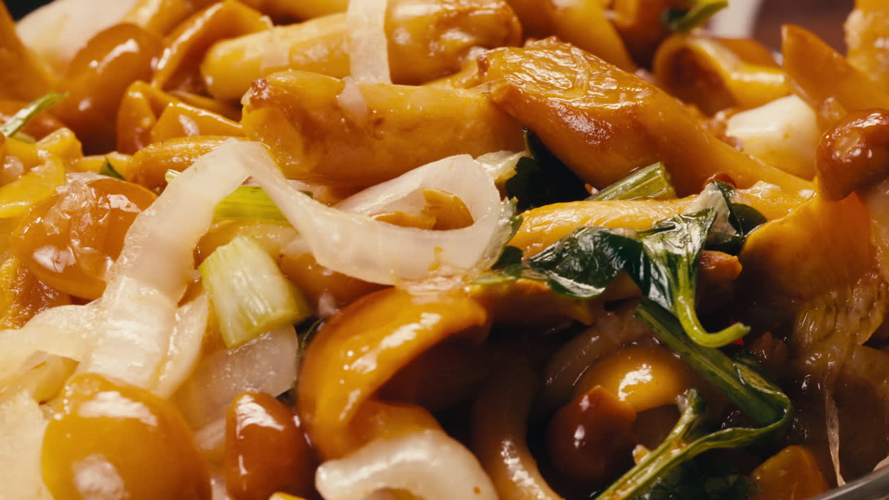 Close-up of fermented yellow honeydew mushrooms with onion on plate. Preservation of vegetables in glass jars. Fermentation preserved mushroom with spices rotating macro.