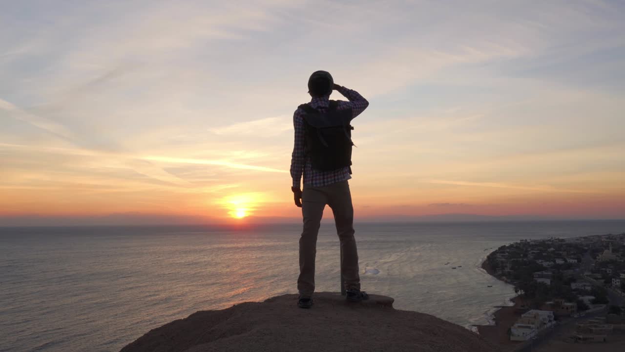 멋진 중동 남성, 드레드 머리카락으로 해가 뜨는 것을 바라보고 있습니다.