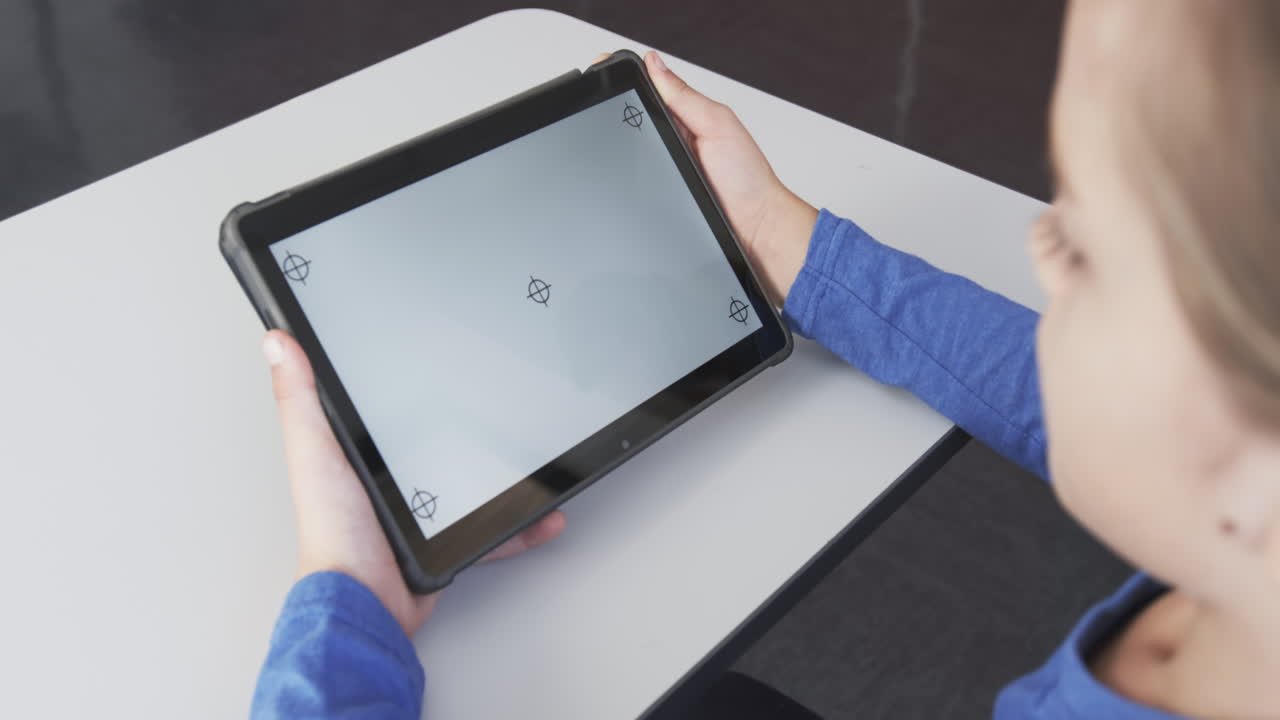 Holding tablet, student in school focusing on screen at desk, copy space