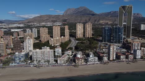 drone panorama shot showing skyline of benidorm town in spain with puig campana mountain in background